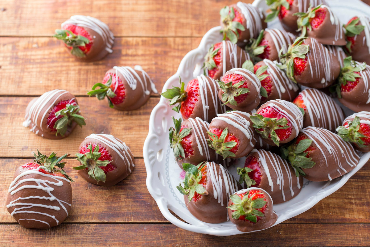 Chocolate-dipped strawberries on a white plate and rustic wooden table